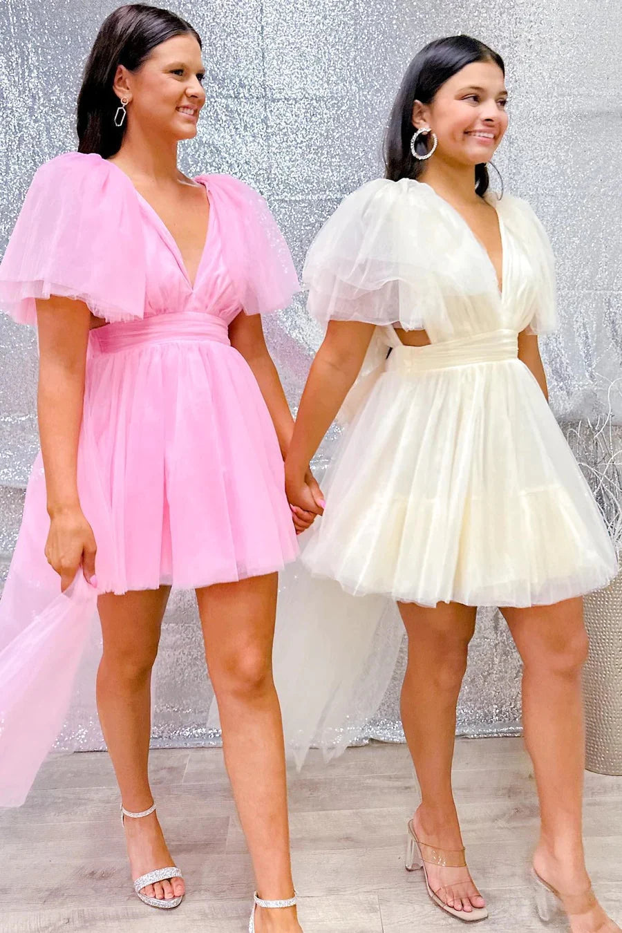 Back view of a pink plunge V A-line homecoming dress with flutter sleeves on a model.