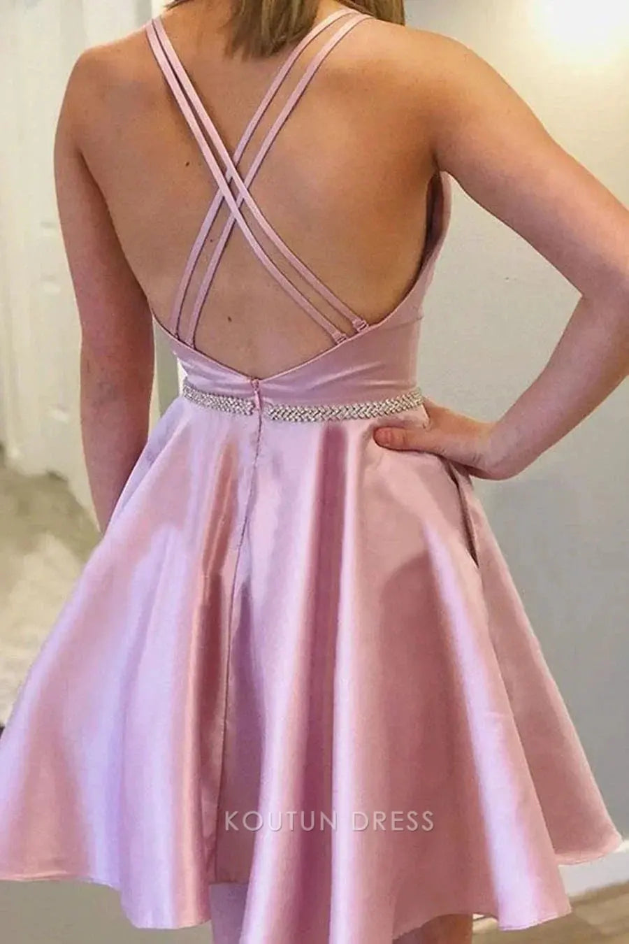 Back view of a blush pink halter mini dress with flowy A-line skirt.