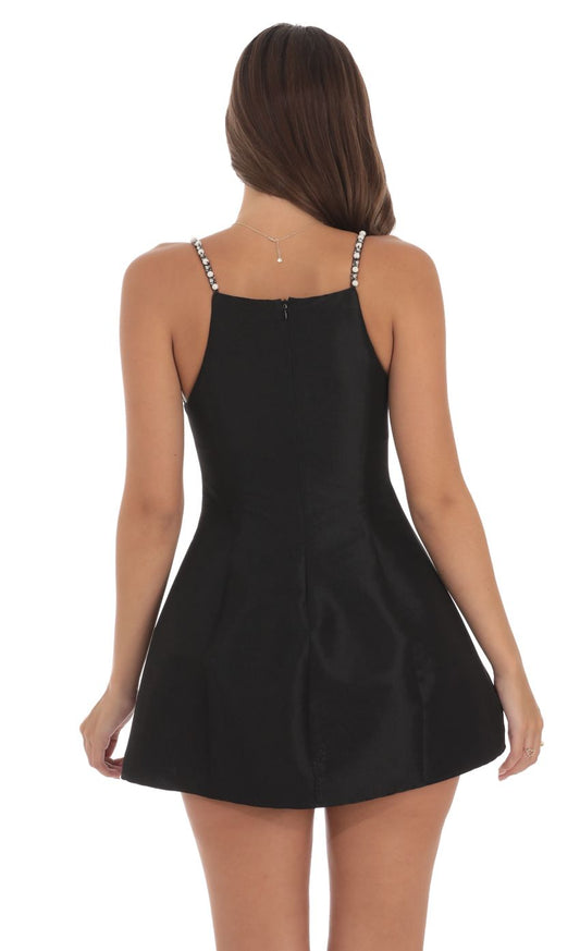 Black A-line flare dress with pearl straps, back view.