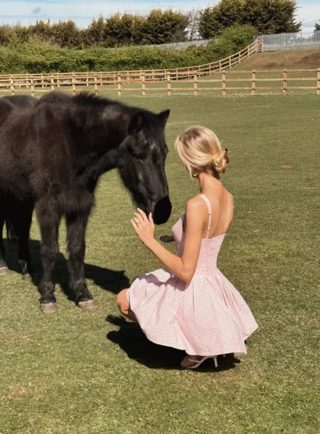 Model posing in a pink polka dot V-neck mini homecoming dress, showing the back detail.
