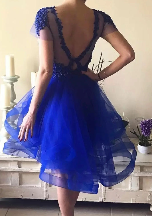 Back view of royal blue A-line high-low homecoming dress with layered tulle skirt.