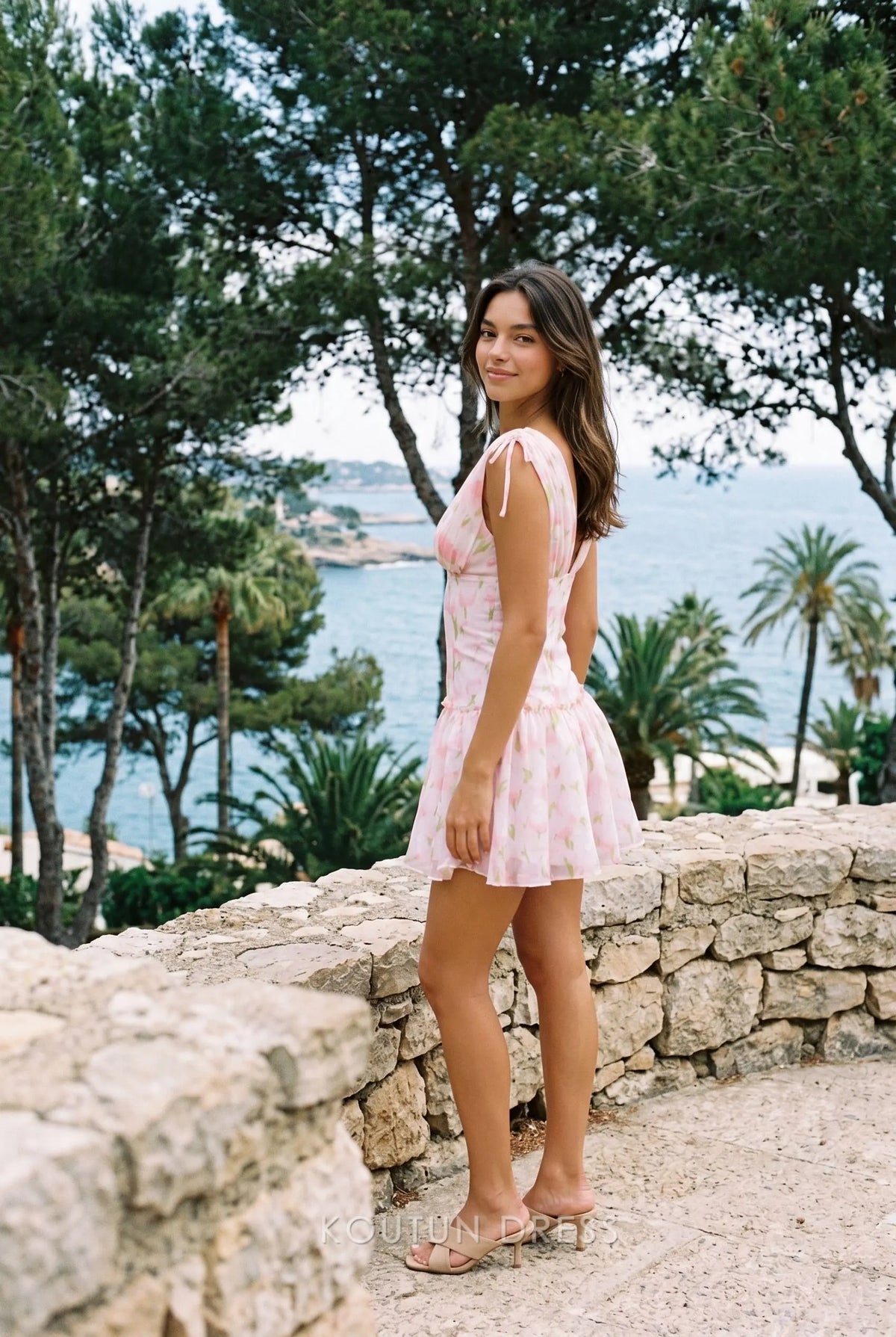Side view of a pink floral chiffon mini dress with tie straps and a flared skirt.