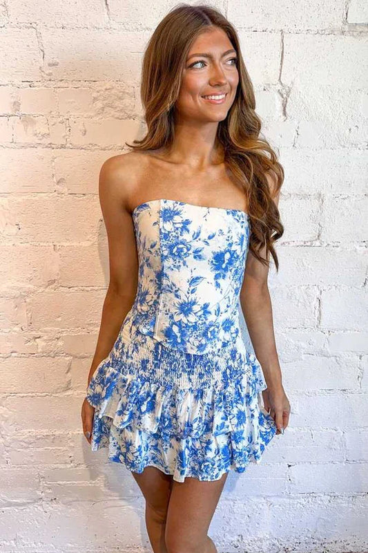 Model wearing a blue and white printed strapless short homecoming dress with ruffles.