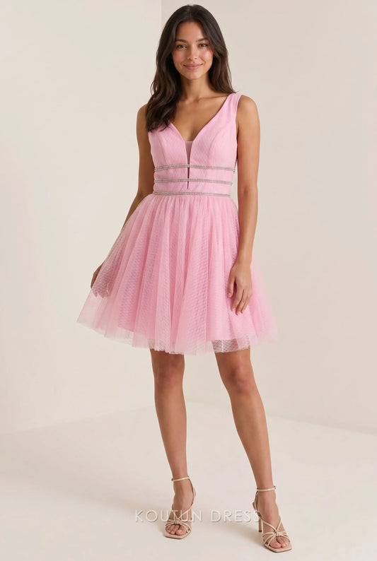 Model wearing a blush pink textured tulle A-line mini homecoming dress with deep V-neck and rhinestone waist, front view.
