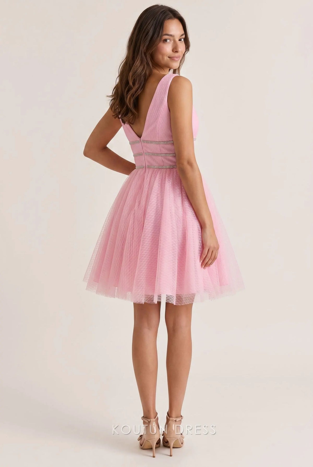 Back view of a blush pink textured tulle mini homecoming dress, showing the deep V open back and flowy A-line skirt.