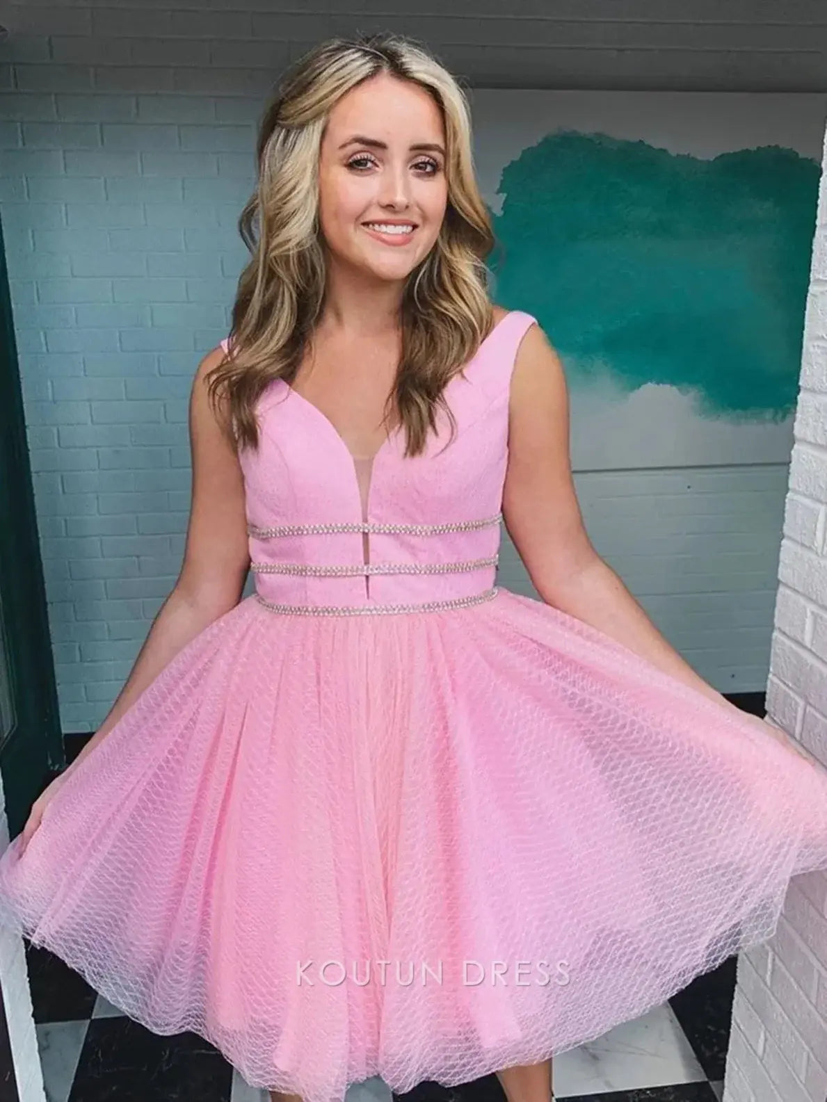 Close-up of the rhinestone embellished waistband and textured blush pink tulle fabric on the mini homecoming dress.