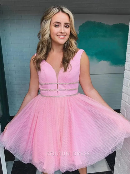 Close-up of the rhinestone embellished waistband and textured blush pink tulle fabric on the mini homecoming dress.