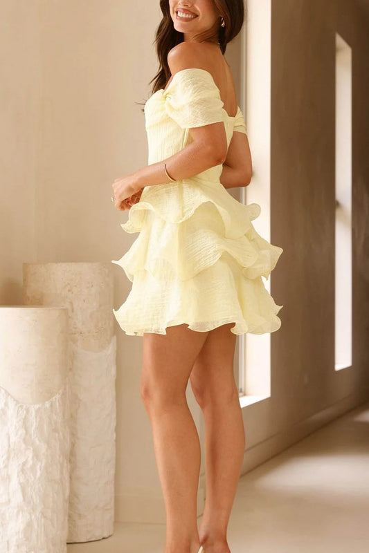 Pastel yellow off-shoulder A-line mini dress, showcasing the tiered ruffle skirt and draped bodice.