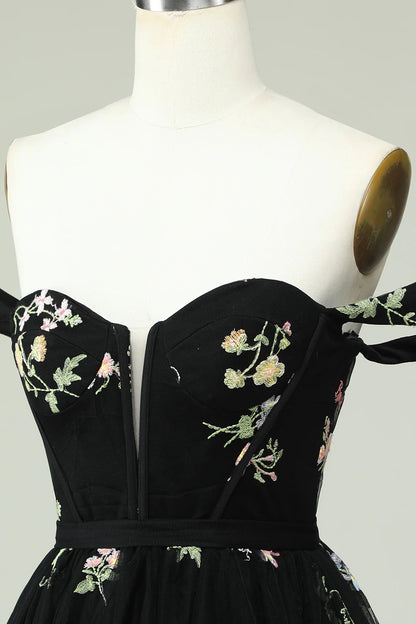 Model wearing a black A-line sweetheart off-shoulder floral print homecoming dress.