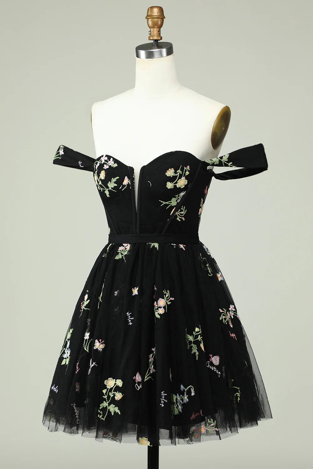 Side view of a model in a black floral print A-line homecoming dress.