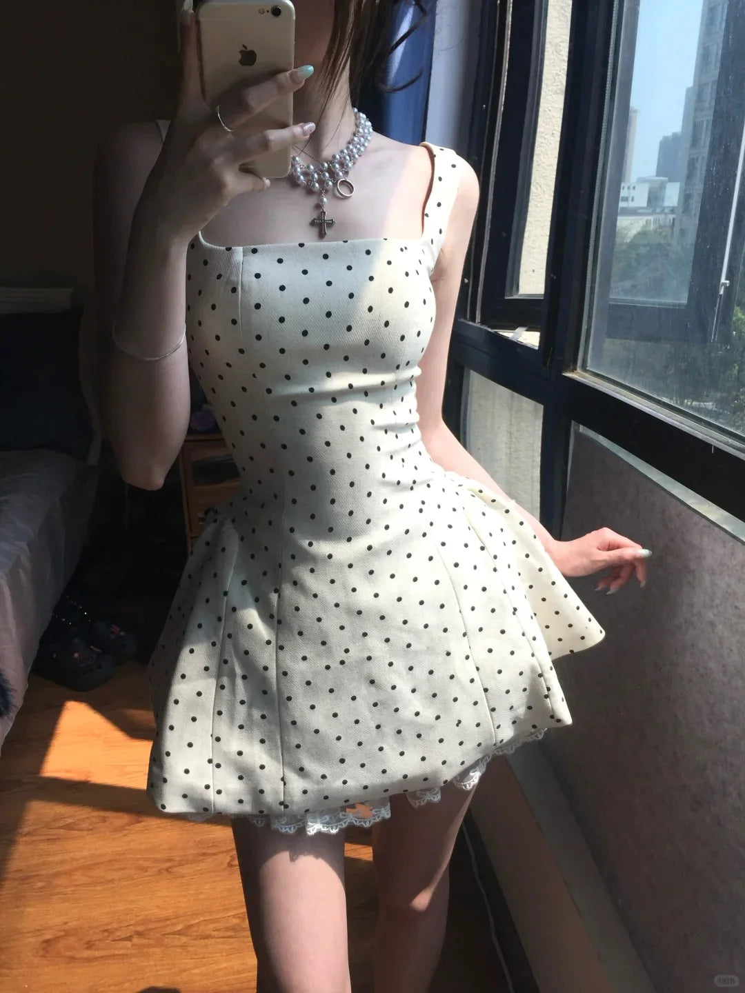Model posing in the white polka dot mini dress, highlighting the flared skirt and lace hem.