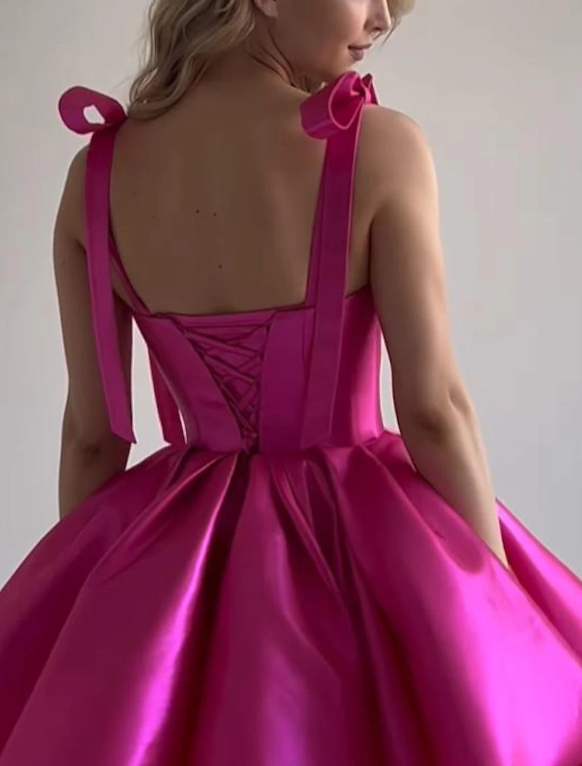 Back view of a pink A-line satin dress with a corset-style back.