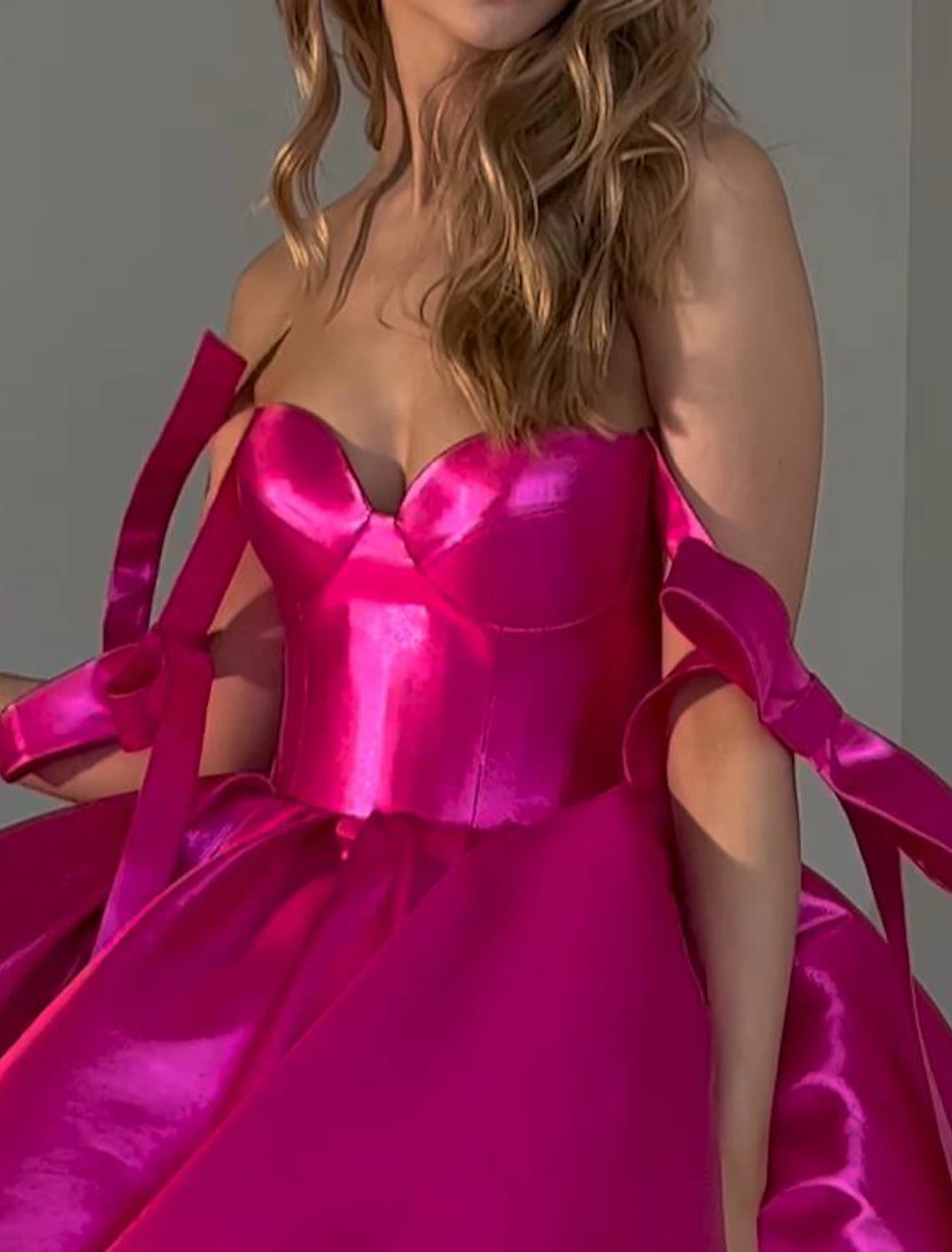Close-up of the bow detail on a pink A-line satin dress.