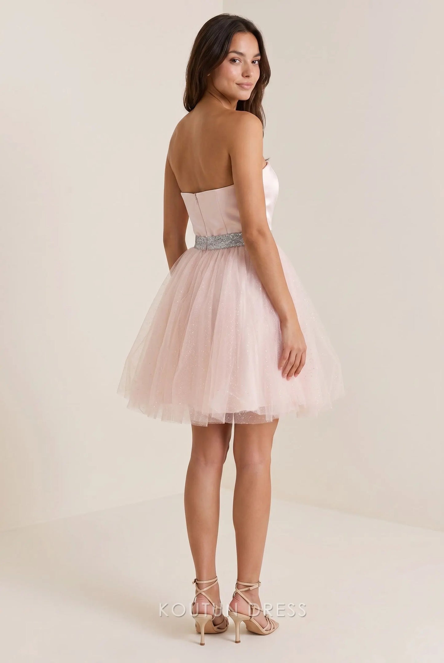 Back view of the blush pink strapless mini dress, showing the open back and glitter tulle skirt.