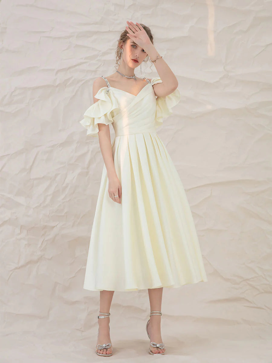 Model wearing a light yellow A-line short prom dress with spaghetti straps.