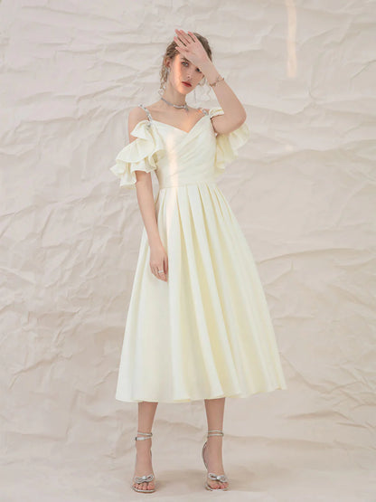 Model wearing a light yellow A-line short prom dress with spaghetti straps.