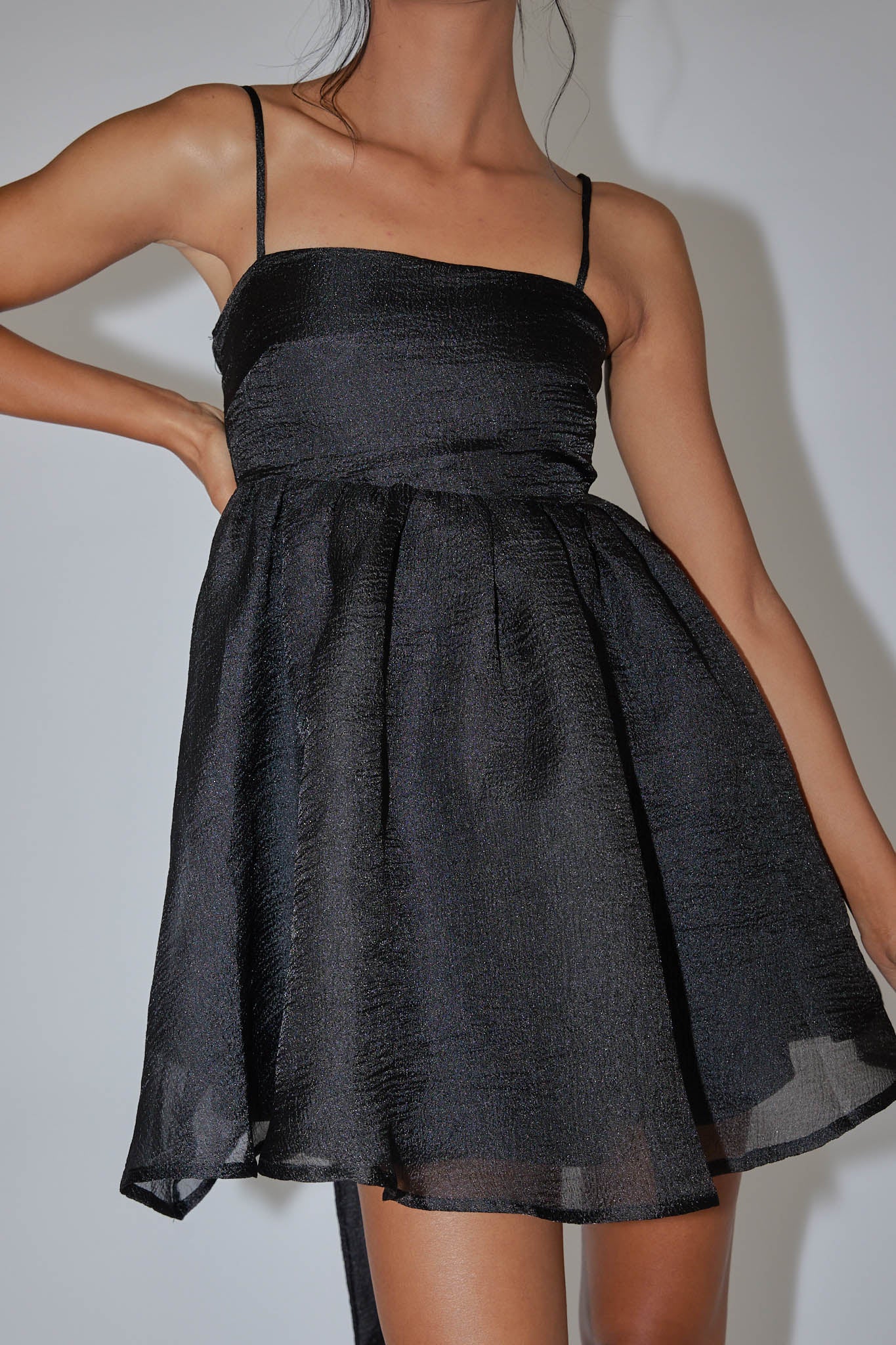 Close-up of the black babydoll dress fabric and spaghetti straps.