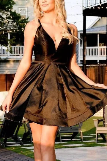 Model wearing a black V-neck empire-waist short homecoming dress with spaghetti straps and a bow detail.