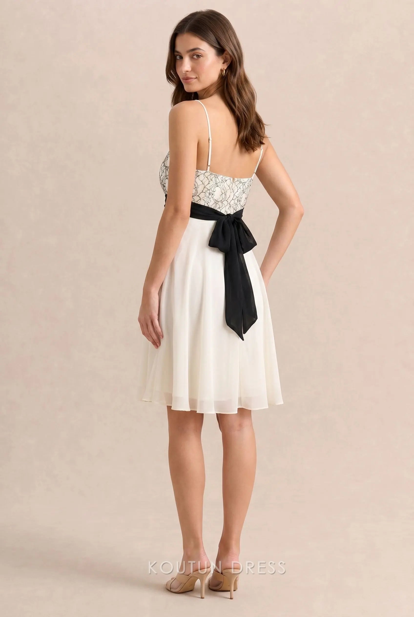 Back view of ivory white homecoming dress with black bow tie detail.