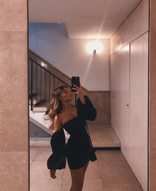 Model wearing a black off-the-shoulder mini homecoming dress.