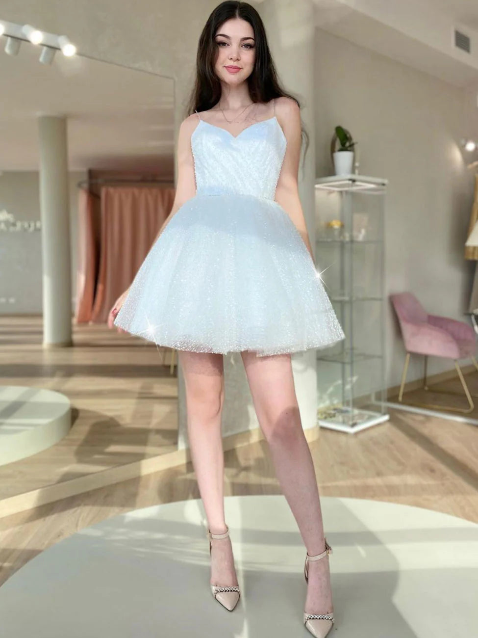 Model wearing a sparkling A-line white mini dress with a sweetheart neckline.
