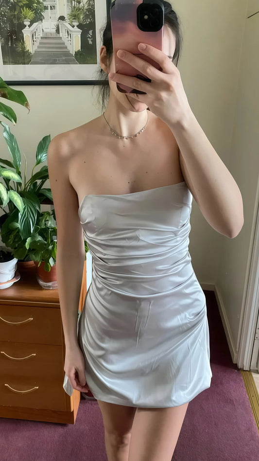 Woman wearing a chic strapless satin mini homecoming dress, front view.