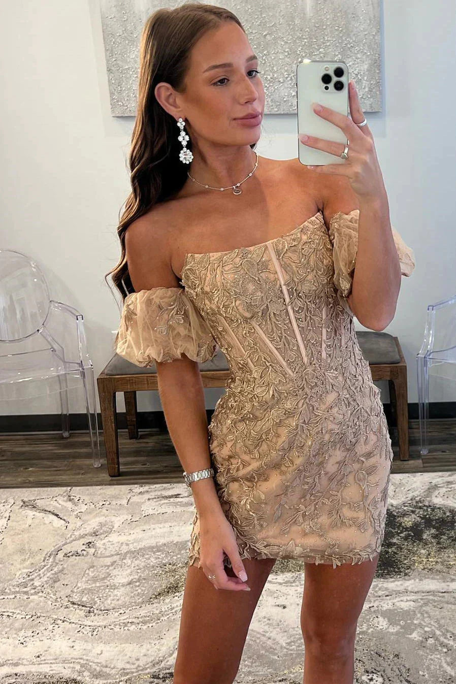 Model wearing a gold strapless bodycon homecoming dress with balloon sleeves and appliques.