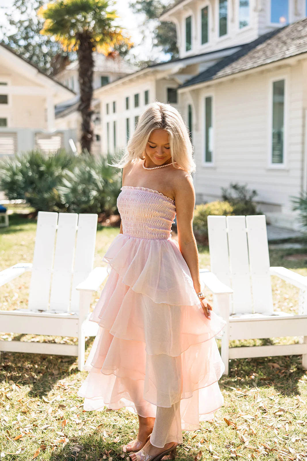 Side view of a soft pink strapless tiered ruffle maxi dress, highlighting the flowy chiffon skirt.