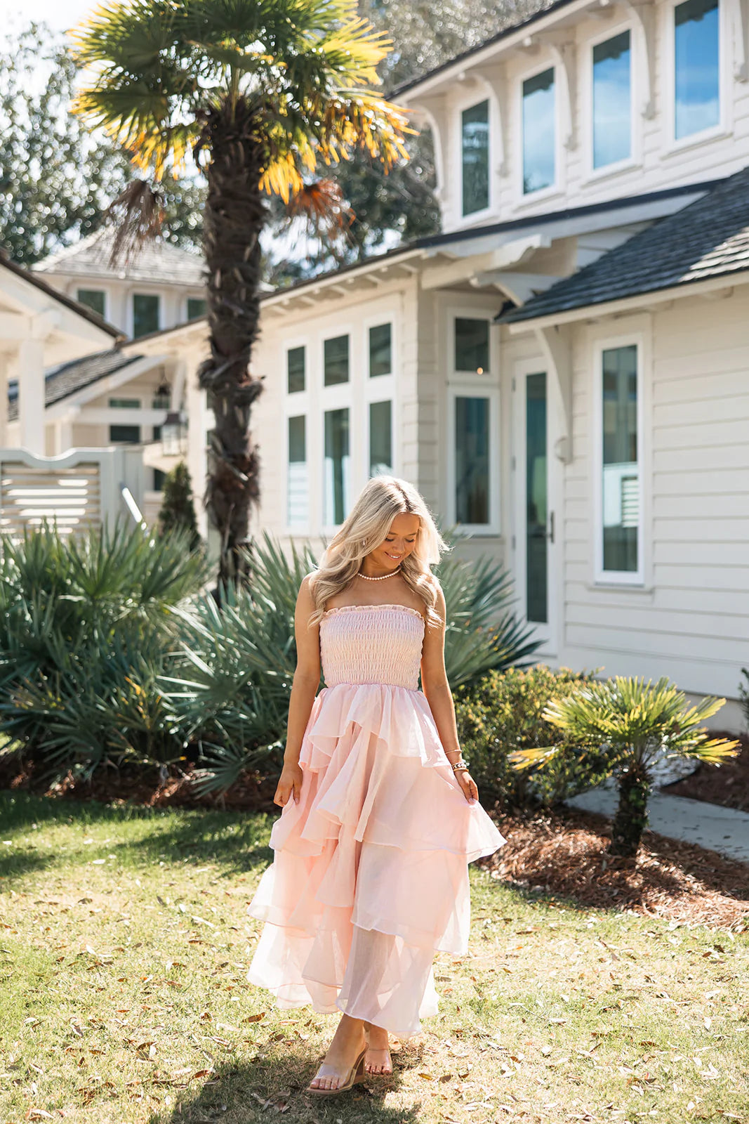 Close-up of the smocked bodice and tiered ruffles on a soft pink strapless dress.