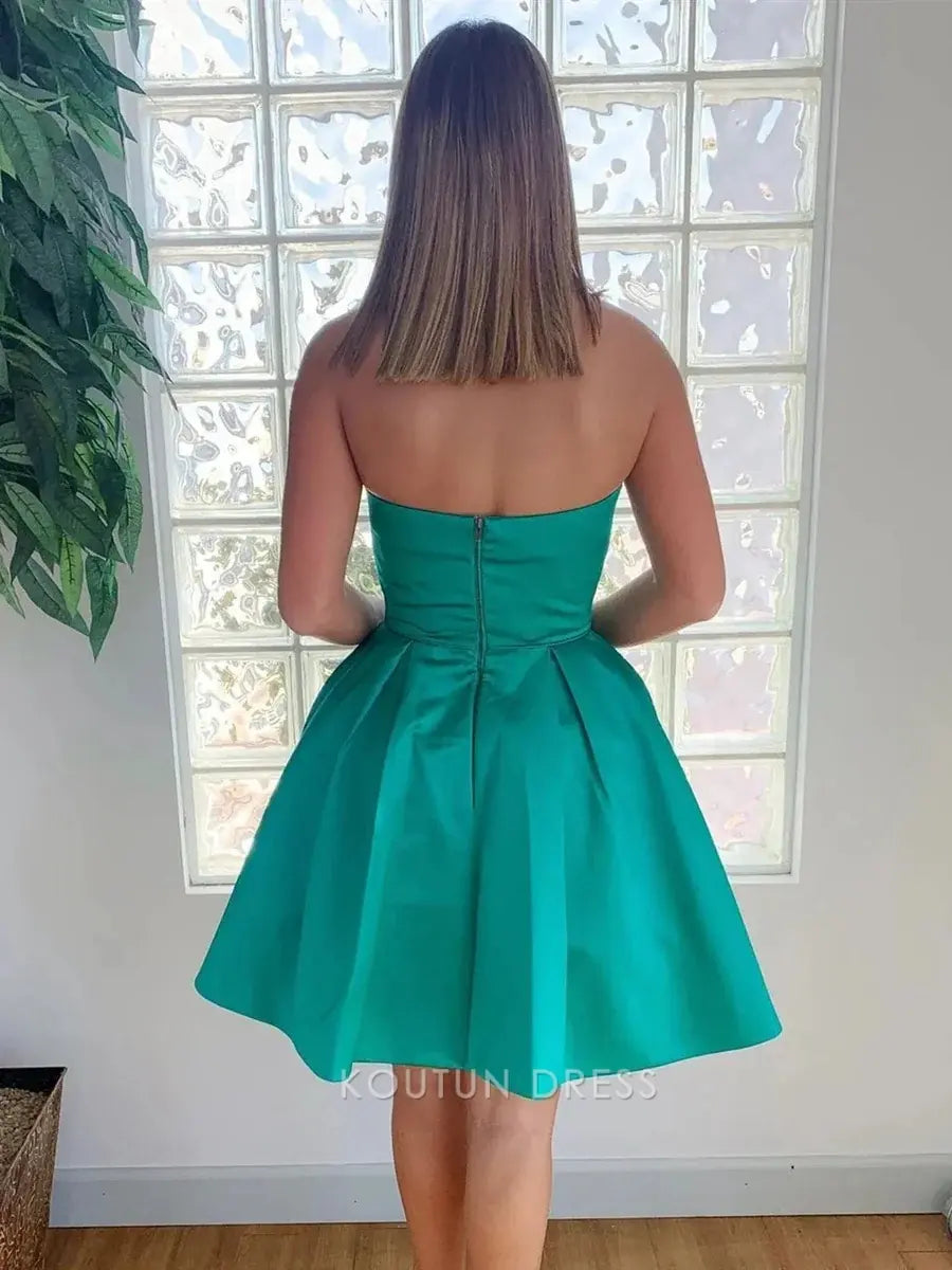 Side view of pleated A-line skirt on emerald green knee-length dress.