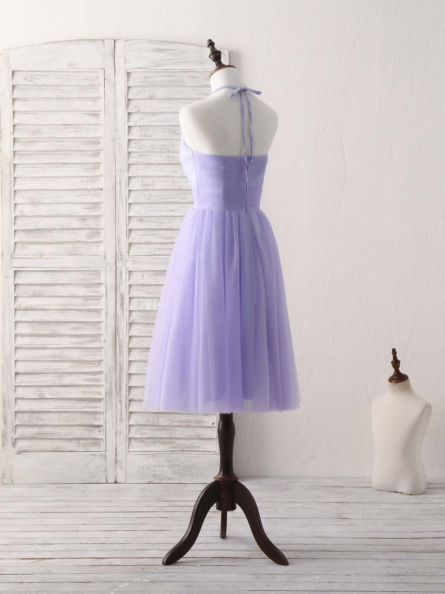 Side view of a woman in a short purple A-line halterneck tulle dress, showing the flowing skirt.