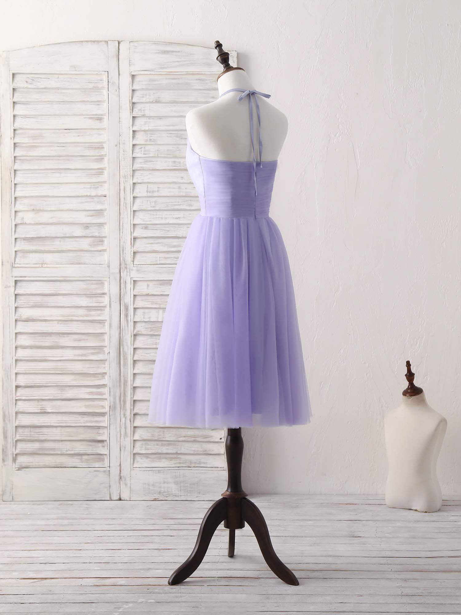 Side view of a woman in a short purple A-line halterneck tulle dress, showing the flowing skirt.