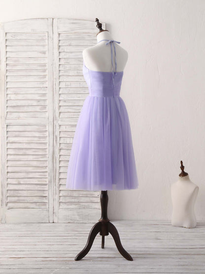Side view of a woman in a short purple A-line halterneck tulle dress, showing the flowing skirt.