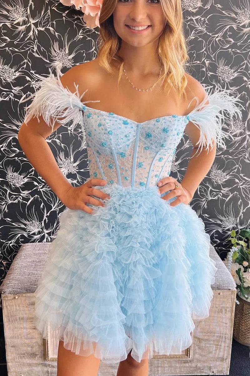 Model wearing a light blue A-line off-shoulder short homecoming dress with feather accents.