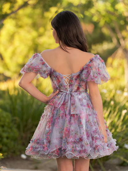 Model posing in a vibrant printed tulle off-shoulder homecoming dress.