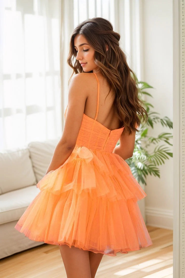 Back view of an orange A-line tulle formal dress, showcasing the flowing skirt and delicate straps.