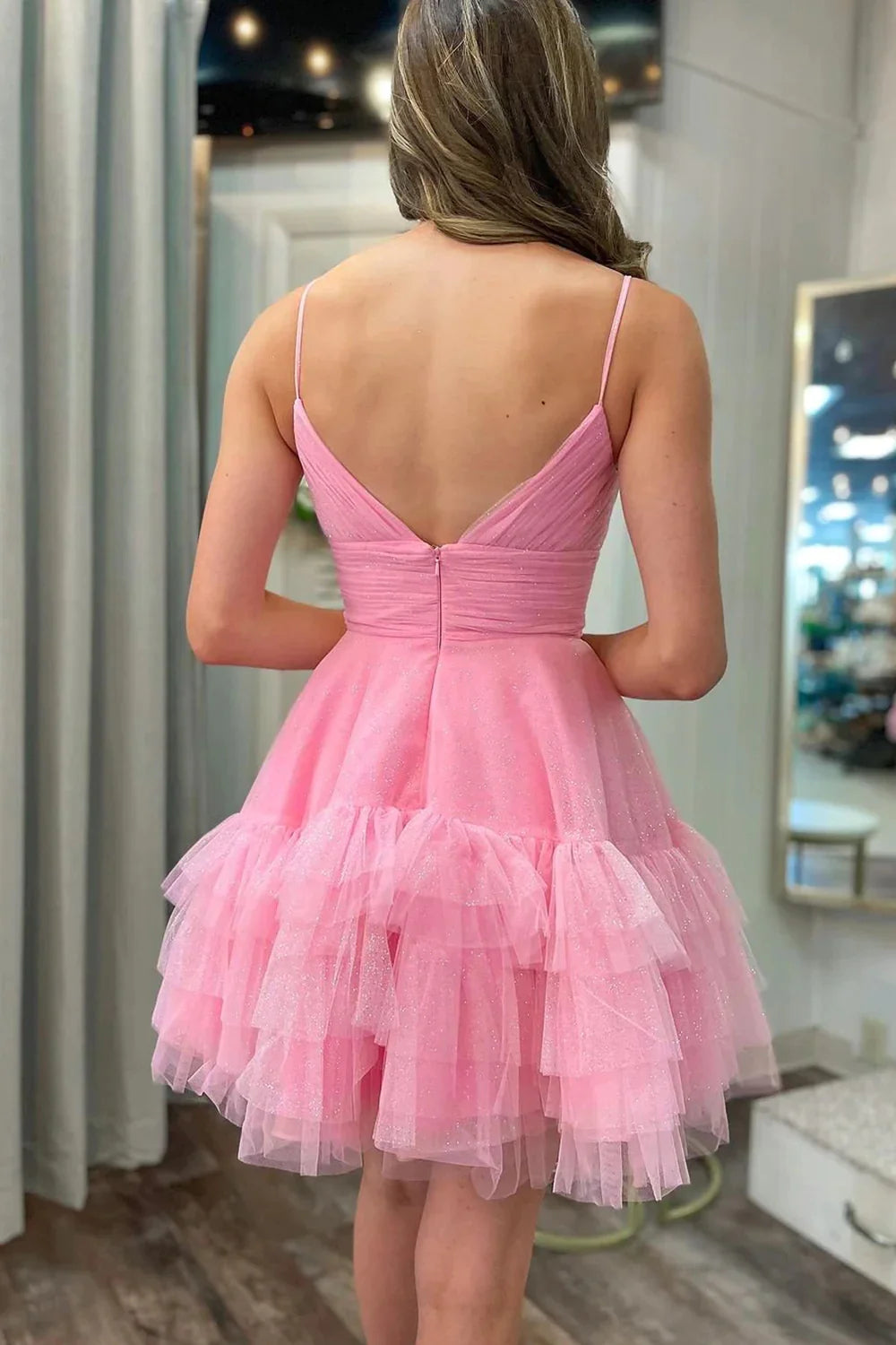 Back view of a pink A-line short homecoming dress with spaghetti straps and ruffles.