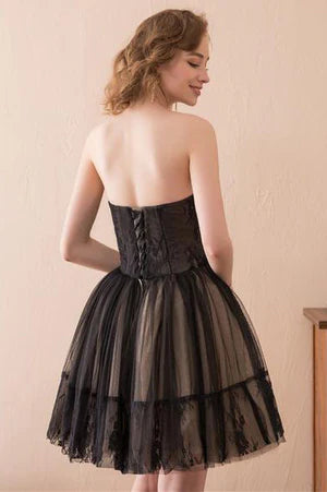 Model wearing a short black strapless A-line tulle dress.