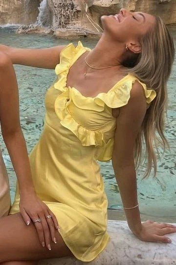 Yellow satin homecoming dress with spaghetti straps, ruffles, and pleats.