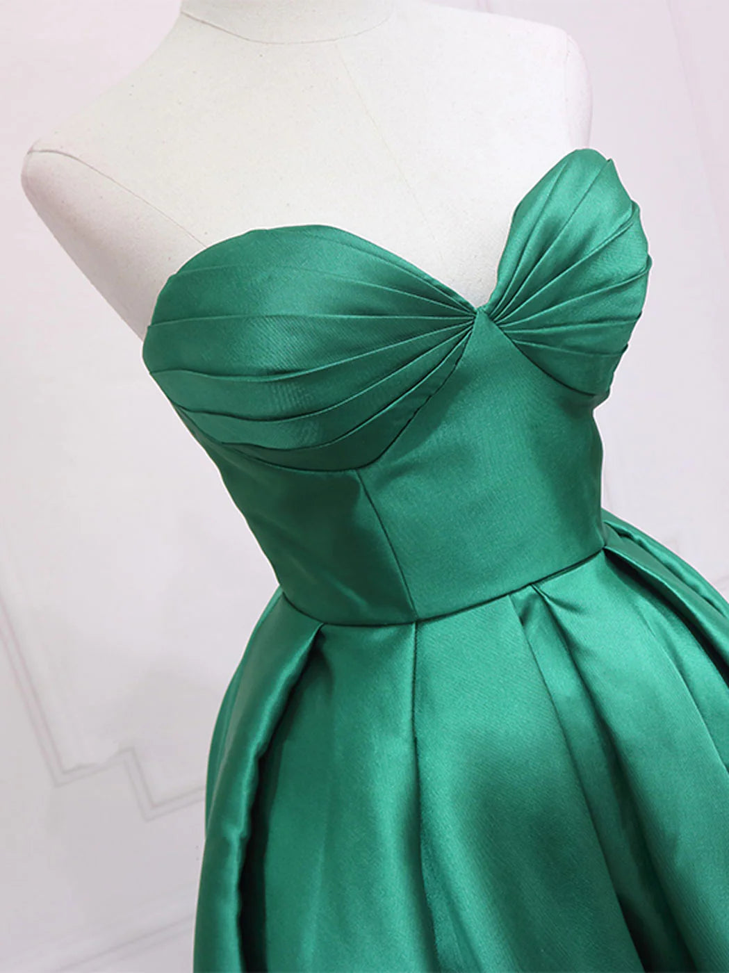 Side view of a flowing green high-low dress with sweetheart neckline.