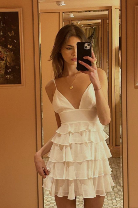 Model wearing a rose gold A-line homecoming dress with spaghetti straps and ruffles.