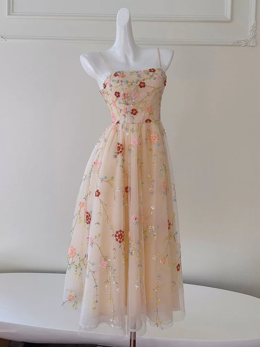 Front view of an A-Line champagne pink tea-length prom dress with a sequin bodice and flowing tulle skirt.