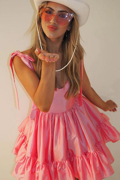 Model posing gracefully in a coral satin short homecoming dress, showing movement.