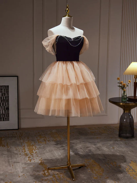 Model wearing a champagne and black sweetheart short tulle homecoming dress, front view.