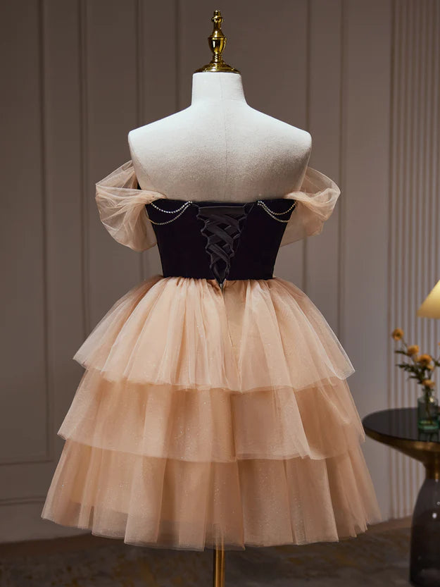 Model in a champagne and black short formal dress, side view, showcasing the tulle skirt.