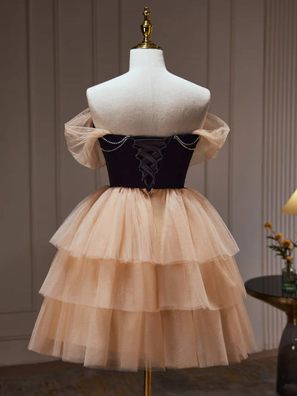 Model in a champagne and black short formal dress, side view, showcasing the tulle skirt.