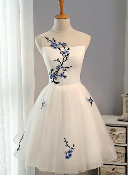 Model wearing a white tulle knee-length graduation dress with a sweetheart neckline.