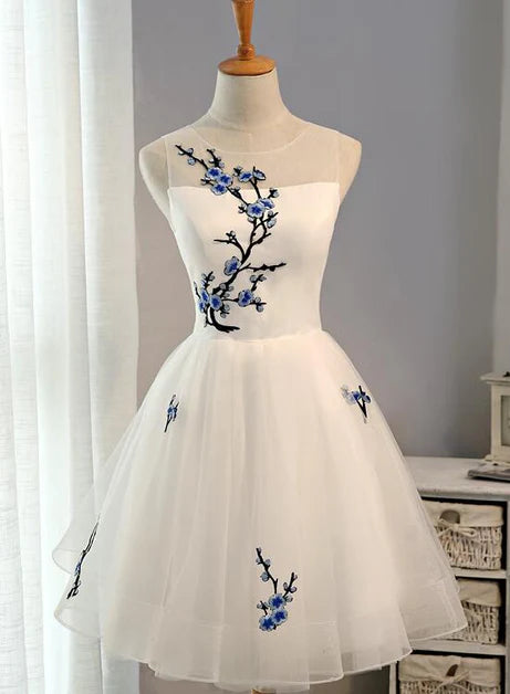 Model wearing a white tulle knee-length graduation dress with a sweetheart neckline.