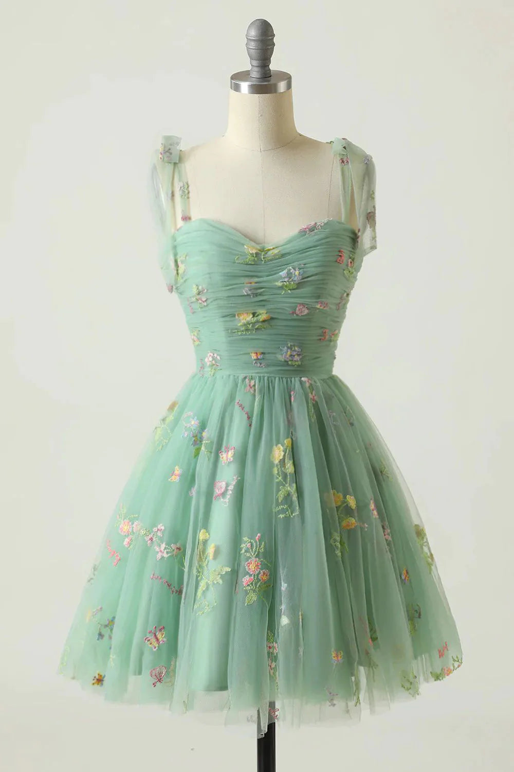 Green A-line dress with spaghetti straps, highlighting the detailed floral embroidery.