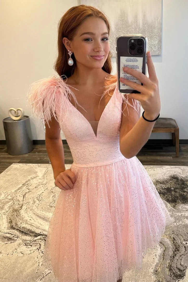 Close-up of the V-neckline and feathered shoulder detail on the pink dress.
